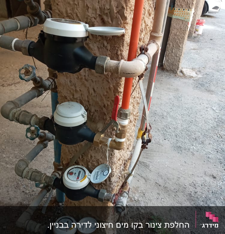 מד מים עם צינורות וברזים מותקנים על קיר